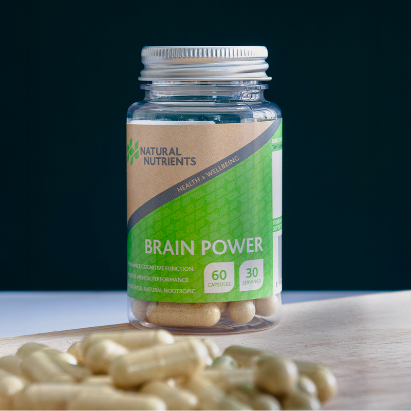 Bottle of 'Brain Power' capsules with a green label on a wooden surface against a dark background